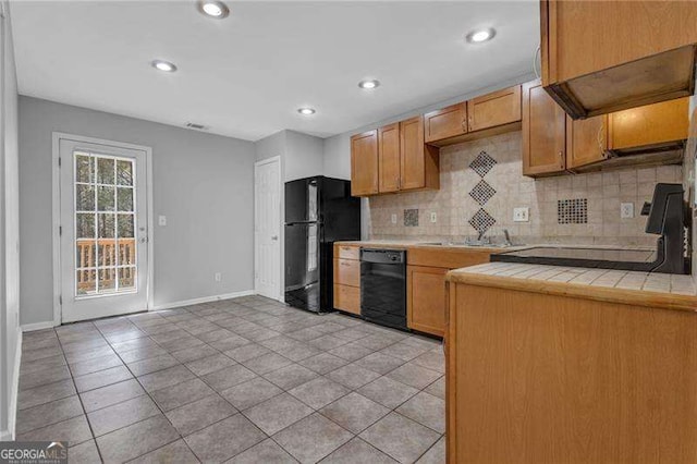 kitchen featuring tile countertops, light tile patterned floors, a sink, black appliances, and tasteful backsplash