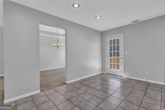 spare room with tile patterned floors, visible vents, baseboards, and a notable chandelier