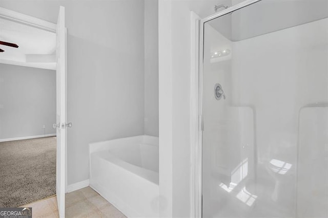 full bath featuring a stall shower, baseboards, a ceiling fan, and a garden tub