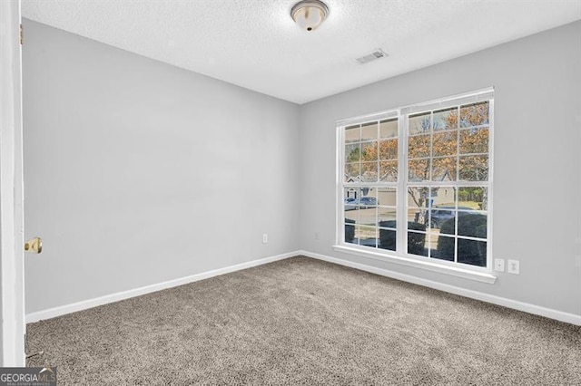 carpeted empty room with baseboards, visible vents, and a textured ceiling