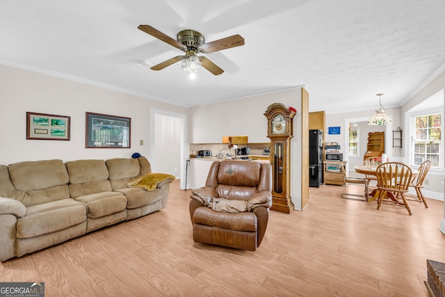 living room with ornamental molding, light wood-style floors, and ceiling fan