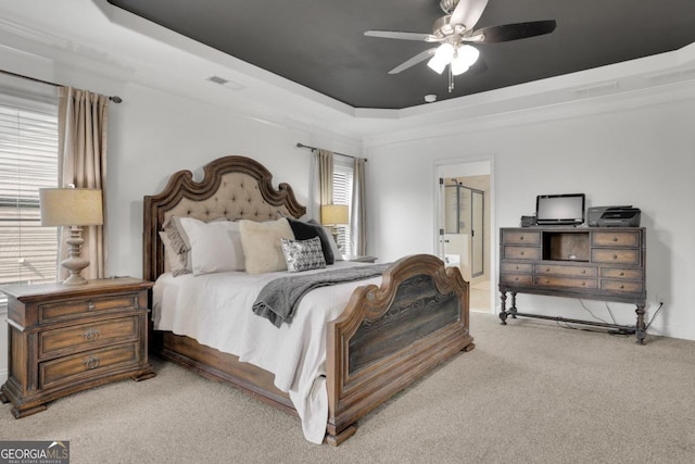 carpeted bedroom featuring ensuite bath, ceiling fan, visible vents, and a raised ceiling
