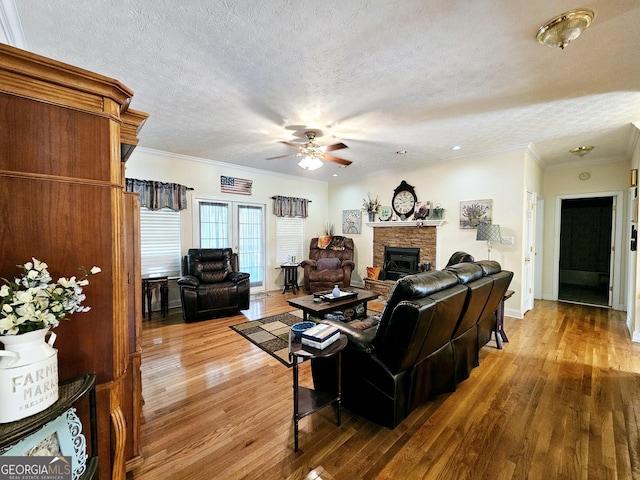 403 Holiday Rd, Franklin, GA 30217 - living area featuring wood finished floors, a ceiling fan, a stone fireplace, a textured ceiling, and crown molding