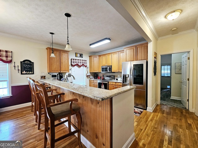 403 Holiday Rd, Franklin, GA 30217 - kitchen featuring wood finished floors, a peninsula, ornamental molding, stainless steel appliances, and a kitchen breakfast bar