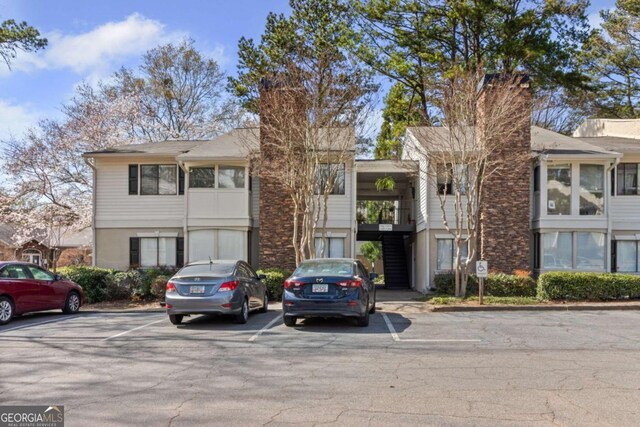 view of property with stairway and uncovered parking