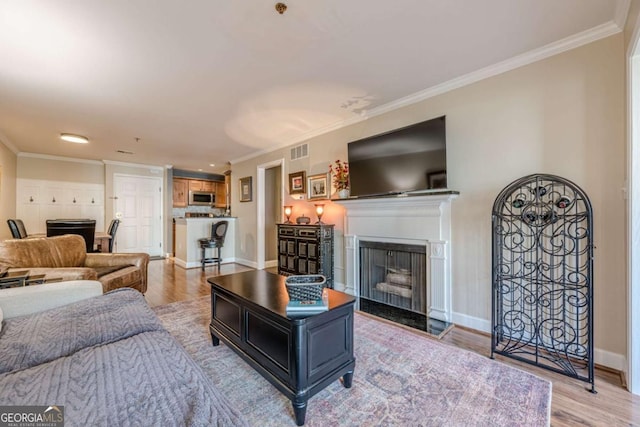 living room featuring visible vents, ornamental molding, wood finished floors, and a fireplace