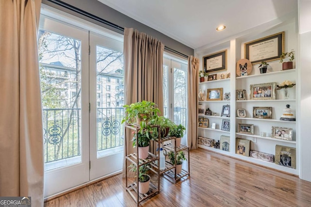 living area featuring light wood finished floors, baseboards, a fireplace with flush hearth, visible vents, and ornamental molding