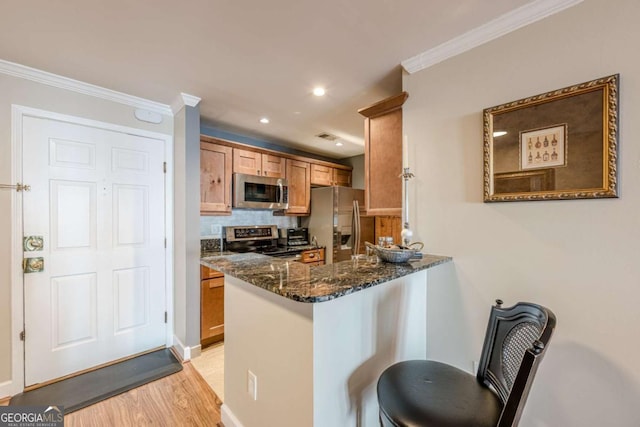 kitchen with a sink, dark stone countertops, brown cabinets, and tasteful backsplash