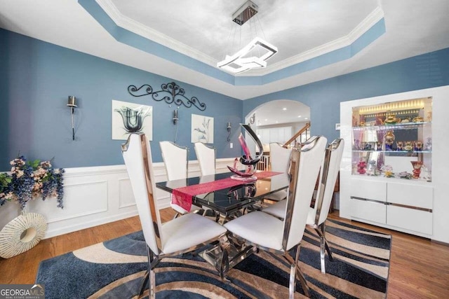 3015 Gold Creek Dr, Villa Rica, GA 30180 - dining room featuring a raised ceiling, arched walkways, wood finished floors, crown molding, and a wainscoted wall