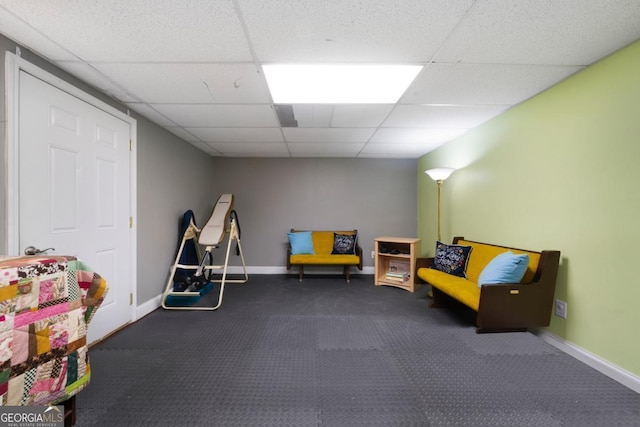 recreation room with a paneled ceiling and baseboards