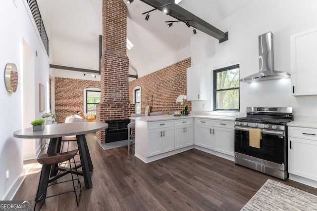 6592 Factory Shoals Rd SW, Mableton, GA 30126 - kitchen with stainless steel gas range, wall chimney exhaust hood, brick wall, a peninsula, and white cabinetry