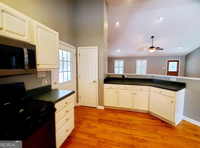 kitchen featuring light wood-style flooring, stainless steel microwave, dark countertops, black electric range, and ceiling fan
