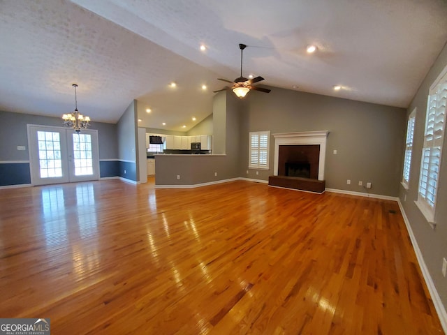 unfurnished living room featuring a fireplace with raised hearth, light wood-type flooring, and a healthy amount of sunlight