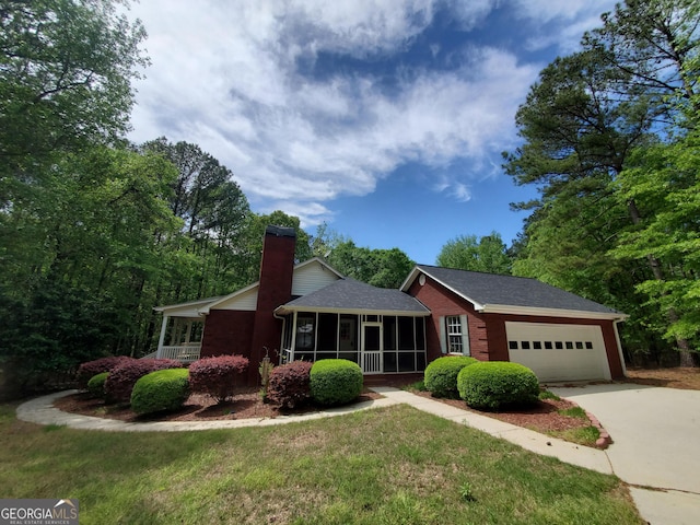 single story home featuring a chimney, a shingled roof, concrete driveway, an attached garage, and a sunroom