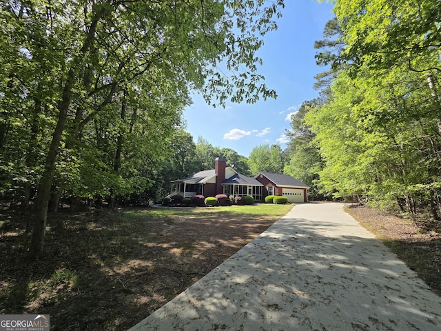 view of front facade with a garage, a chimney, and concrete driveway