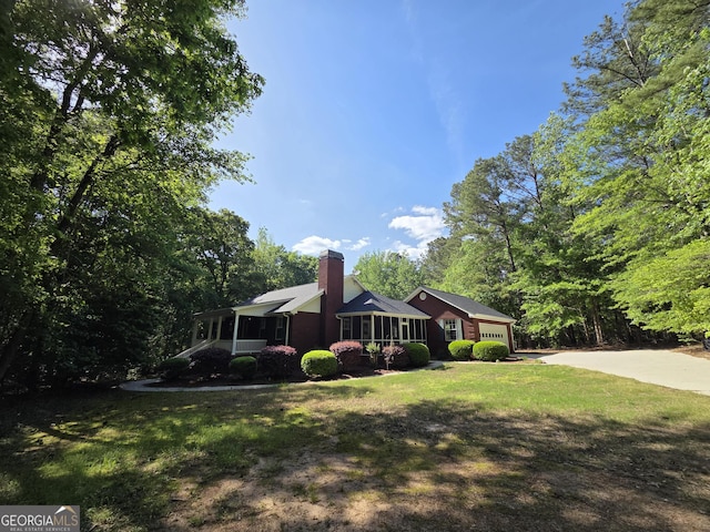 view of front of property featuring an attached garage, driveway, a chimney, and a front yard