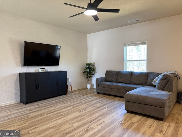 living area with light wood-type flooring, ceiling fan, and baseboards