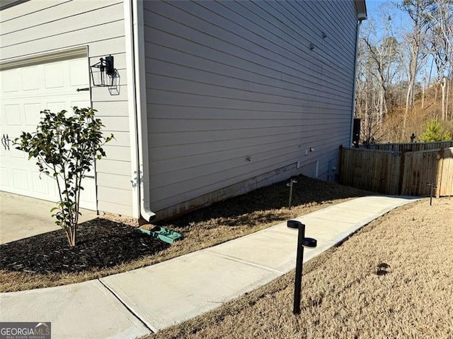 view of side of home featuring fence and an attached garage