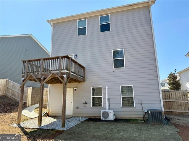 rear view of house featuring central AC unit, a fenced backyard, a wooden deck, and ac unit