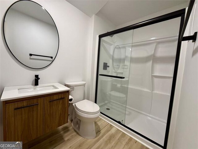 full bathroom featuring wood finished floors, toilet, a shower stall, and vanity