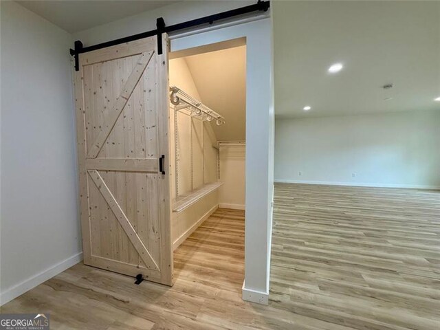 walk in closet featuring a barn door and wood finished floors