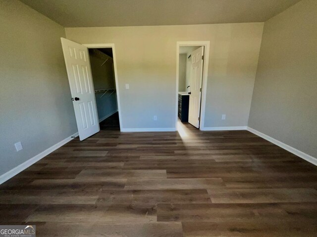 1350 Dogwood Rd, Woodville, GA 30669 - unfurnished bedroom with a walk in closet, ensuite bathroom, baseboards, dark wood-style floors, and a closet