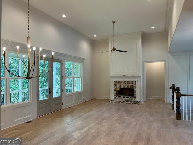 7 Fontaine Dr, Newnan, GA 30263 - unfurnished living room with a ceiling fan, a fireplace, light wood-style floors, a chandelier, and baseboards