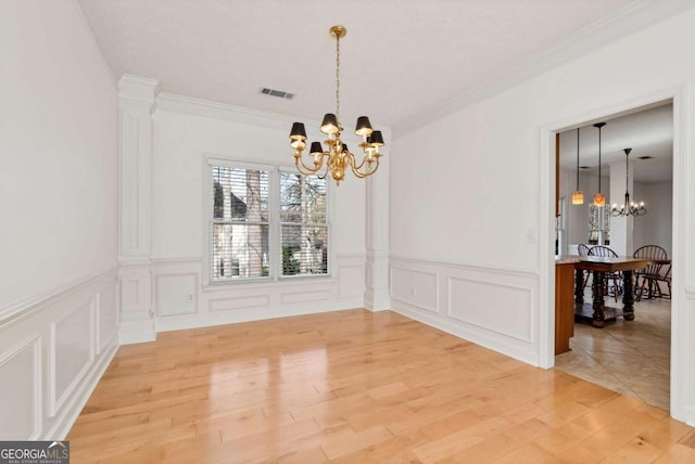 2002 Stonewick Ct, Lawrenceville, GA 30043 - unfurnished dining area with a chandelier, a decorative wall, ornamental molding, light wood-type flooring, and wainscoting