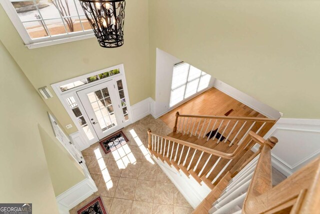 2002 Stonewick Ct, Lawrenceville, GA 30043 - tiled entryway featuring a towering ceiling, plenty of natural light, a chandelier, a wainscoted wall, and stairs