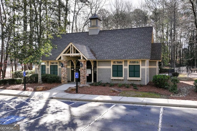 2002 Stonewick Ct, Lawrenceville, GA 30043 - view of front of house featuring a shingled roof, uncovered parking, a chimney, and stone siding