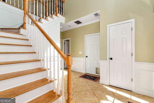 2002 Stonewick Ct, Lawrenceville, GA 30043 - stairs with wainscoting, a decorative wall, tile patterned flooring, ornamental molding, and a towering ceiling