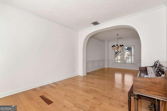 2002 Stonewick Ct, Lawrenceville, GA 30043 - dining area with ornamental molding, a chandelier, arched walkways, light wood-style floors, and a wainscoted wall