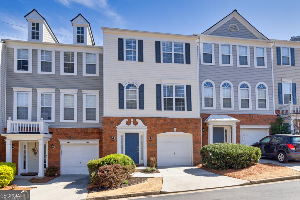 townhome / multi-family property with an attached garage, brick siding, and driveway
