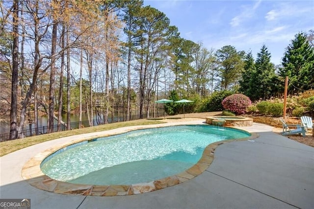 view of pool with fence, a pool with connected hot tub, and a patio area