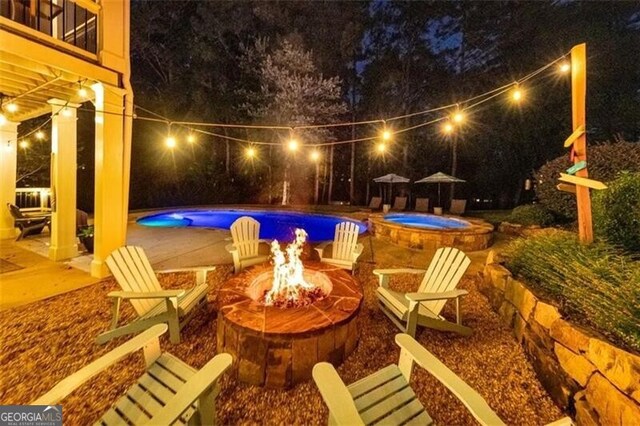 pool at twilight with an outdoor fire pit, an in-ground hot tub, an outdoor pool, and a patio area