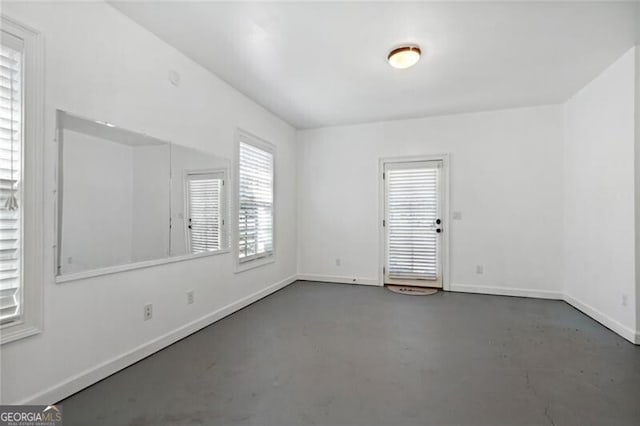unfurnished room with finished concrete floors and baseboards