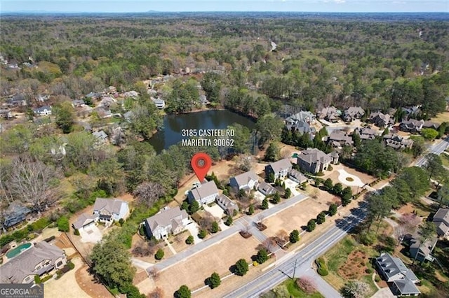 aerial overview of property's location featuring a forest, a nearby body of water, and nearby suburban area