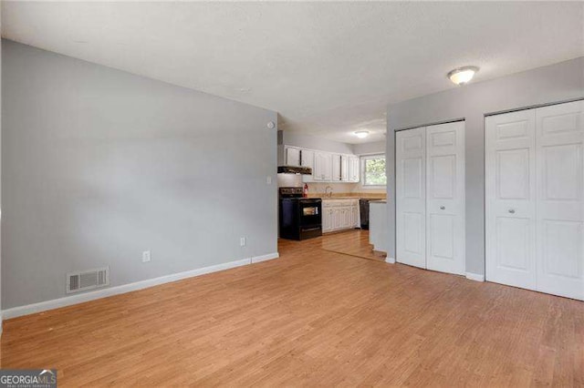 2522 Brentwood Ct, Decatur, GA 30032 - unfurnished living room featuring light wood-type flooring, visible vents, baseboards, and a sink