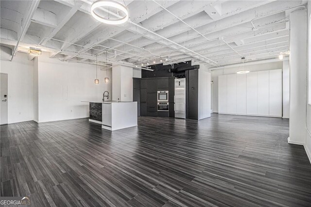 unfurnished living room featuring dark wood-type flooring and a sink