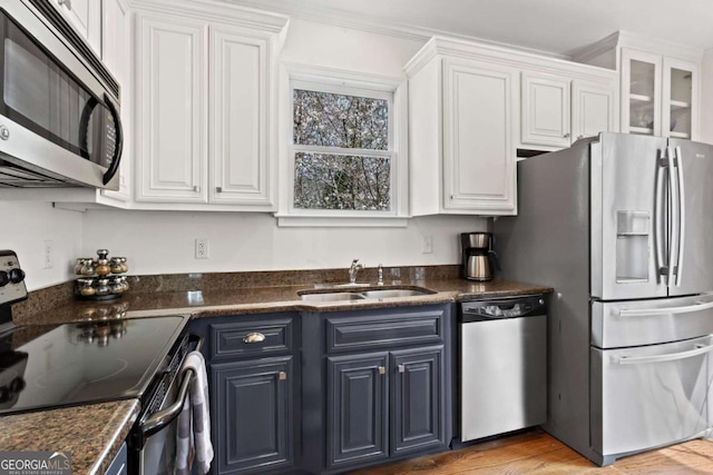 kitchen with white cabinetry, blue cabinets, appliances with stainless steel finishes, and a sink