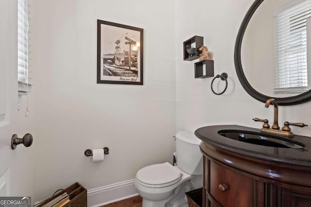 half bath featuring toilet, vanity, and baseboards