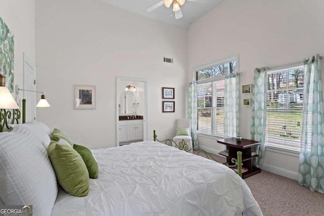 carpeted bedroom with visible vents, high vaulted ceiling, connected bathroom, baseboards, and ceiling fan