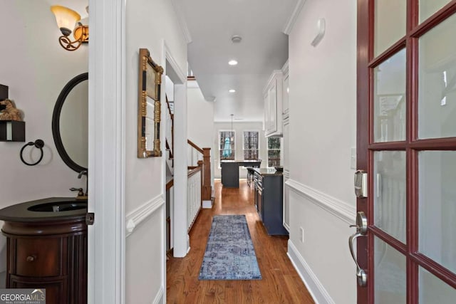 corridor featuring crown molding, baseboards, stairs, recessed lighting, and wood finished floors