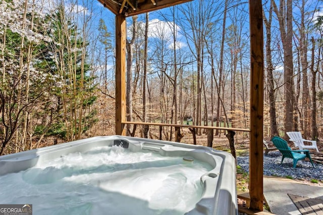 view of patio featuring a wooded view and a hot tub