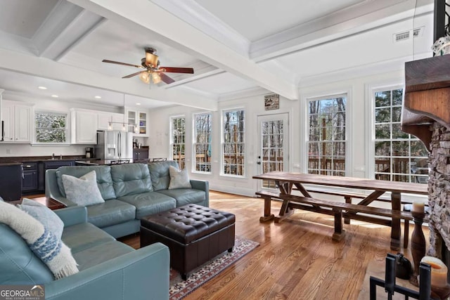 living room featuring visible vents, beamed ceiling, ornamental molding, a ceiling fan, and light wood finished floors