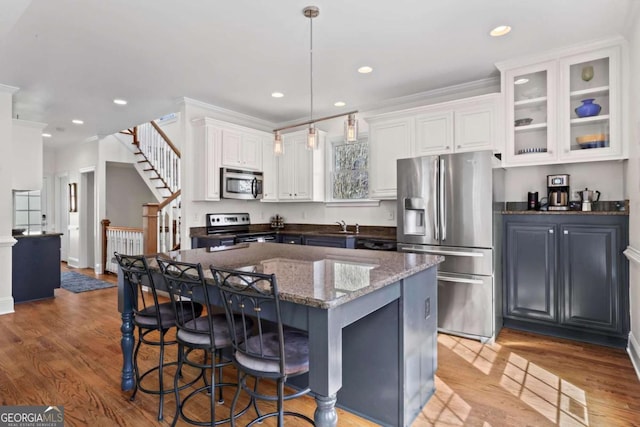 kitchen featuring white cabinetry, a kitchen breakfast bar, light wood-style flooring, and stainless steel appliances