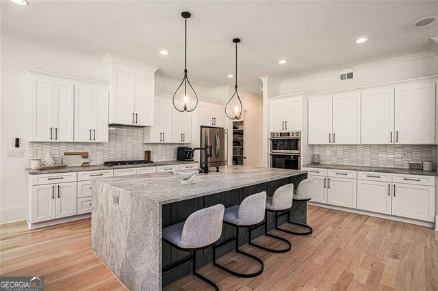 396 Academy St, Alpharetta, GA 30009 - kitchen with appliances with stainless steel finishes, a sink, tasteful backsplash, a kitchen bar, and light wood-style floors