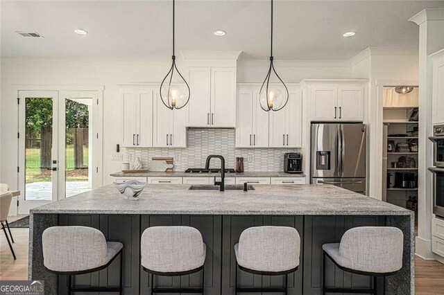 396 Academy St, Alpharetta, GA 30009 - kitchen with stainless steel appliances, wood finished floors, a sink, white cabinetry, and light stone counters