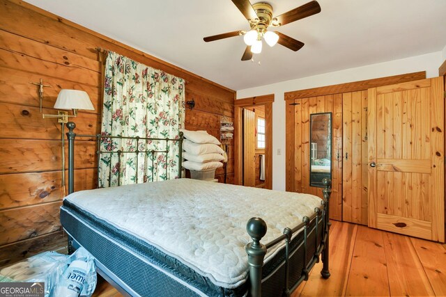 bedroom with wooden walls, wood finished floors, and a ceiling fan