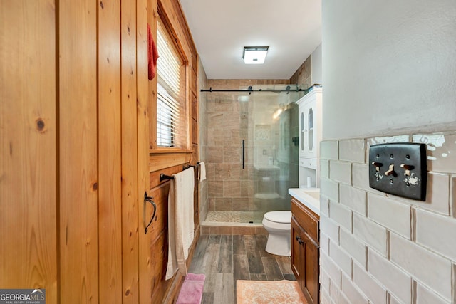 bathroom featuring vanity, a shower stall, toilet, and wood finished floors